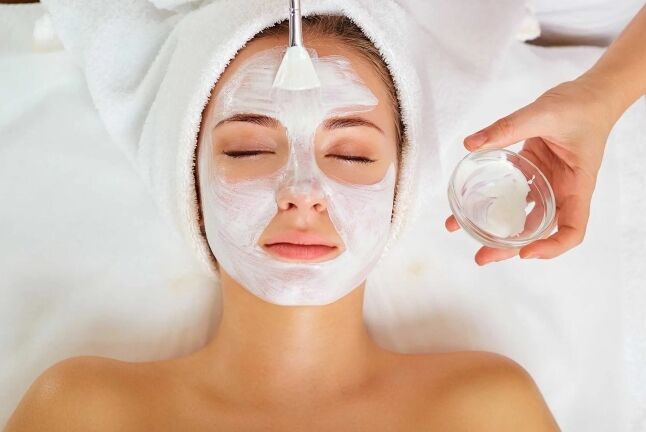 Esthetician applying a collagen facial mask with a brush during a facial in Huntington NY