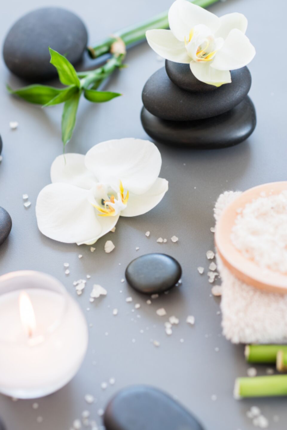 Candles, hot stones, orchids and bamboo laid out for body work at a Huntington spa
